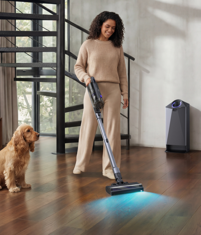 Woman vacuuming a wood floor with the Narwal V50 Cube as a dog sits nearby