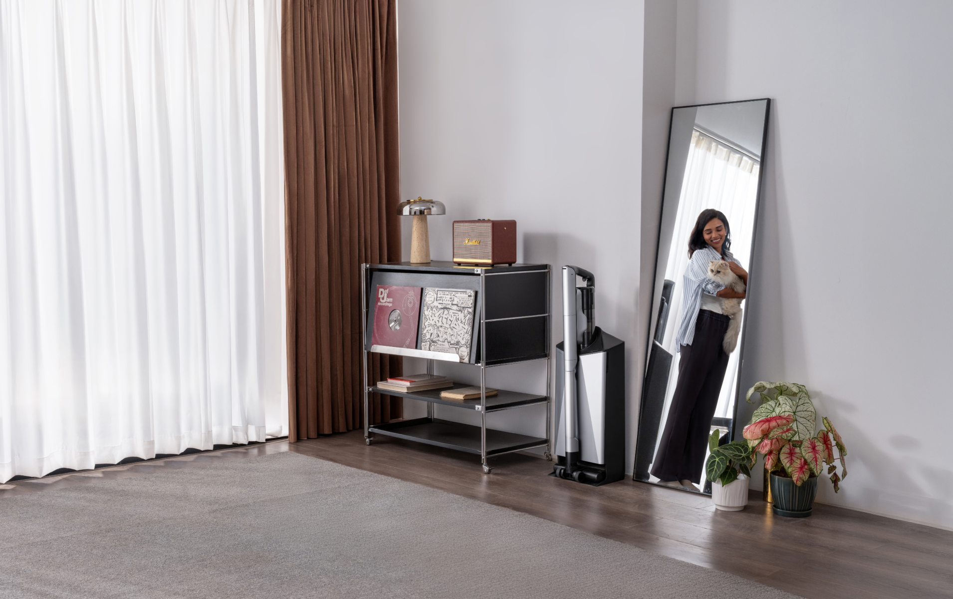 Narwal V50 Cube station beside shelving and a mirror reflecting a woman holding a cat