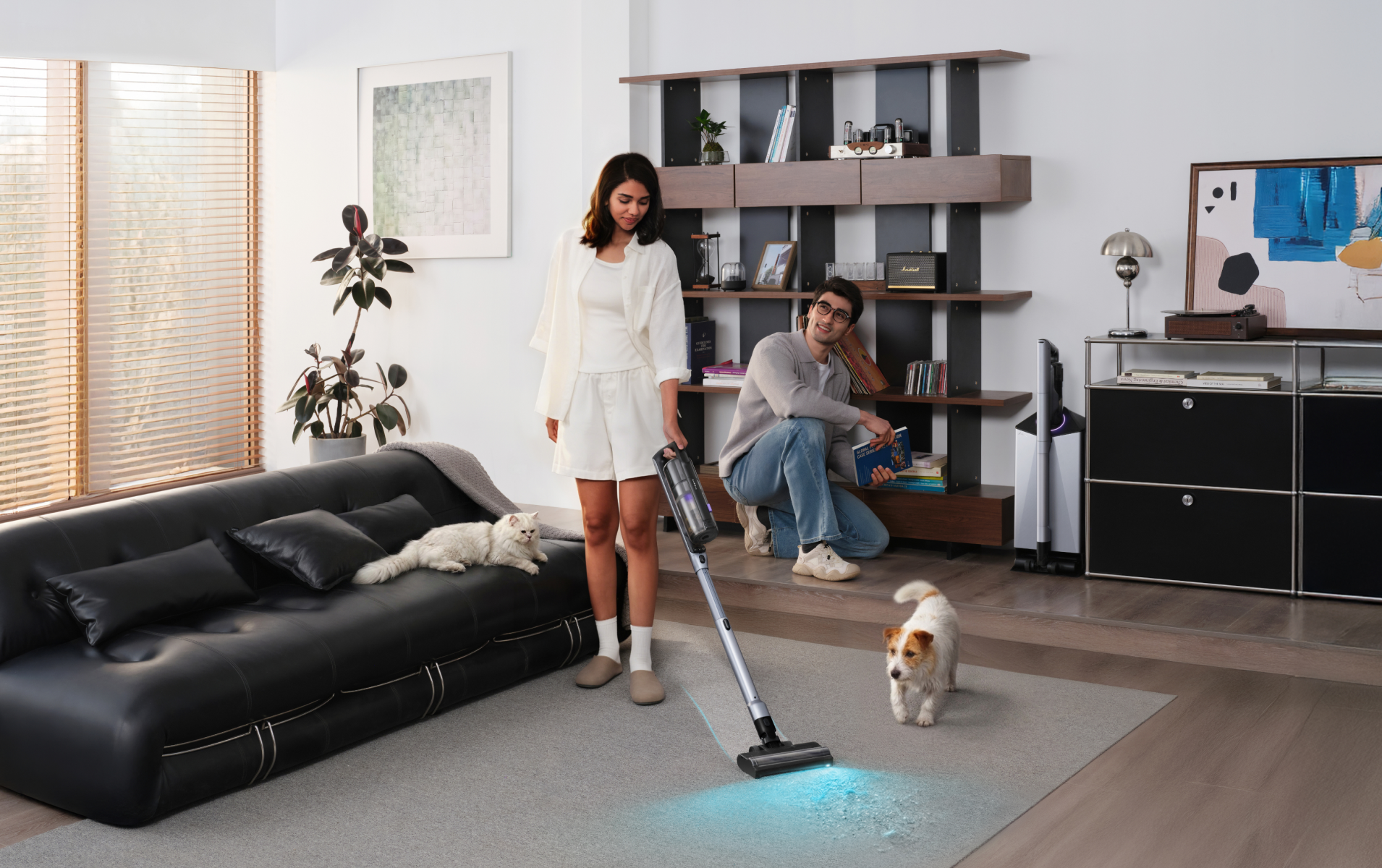 Woman vacuuming a rug with the Narwal V50 Cube while a man and pets look on